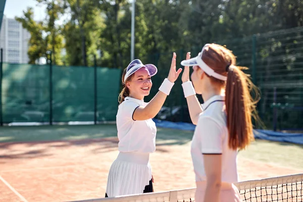 Αξιολάτρευτες ευτυχισμένες γυναίκες που παίζουν τένις μία προς μία. Φιλενάδες που κάνουν αθλητισμό μαζί — Φωτογραφία Αρχείου
