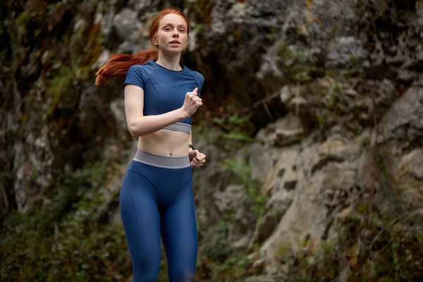 Jonge slanke roodharige vrouw opwarmen op de bergen voor de training, hardlopen — Stockfoto