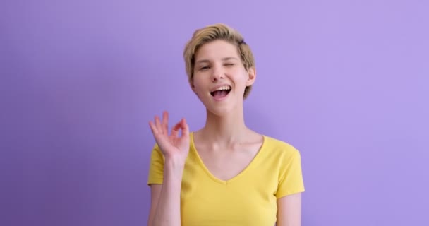 Junge kaukasische Frau trägt lässiges T-Shirt auf lila Hintergrund — Stockvideo