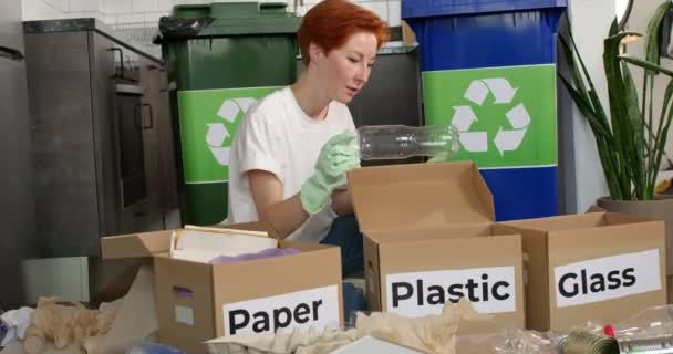 Женщина в повседневной одежде сортирует мусор в картонные коробки во время уборки — стоковое видео