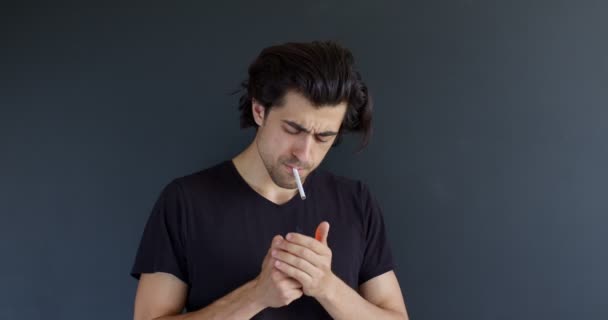 Брюнетка человек, курящий сигарету уверенно, изолированный на черном фоне студии — стоковое видео