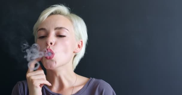 Кавказская стильная женщина курит vape изолированы на черном фоне пространство копирования — стоковое видео