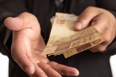 Brezilya para birimini elinde tutuyor ve bir teklif yapıyor. Mali, ödeme ve kredi kavramı.