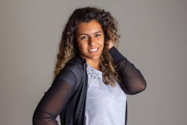 Kameraya bakan genç bir kadının portresi. Siyah insan kıvırcık saçlarına dokunuyor..