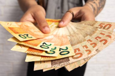 Genç bayan Brezilya 'dan gelen bir miktar parayı sergiliyor. Finansal, kar, kredi, maliyet, satın alma, zengin konsept.