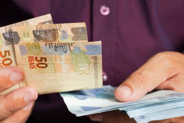 Adam elinde büyük miktarda para tutuyor, Brezilya 'dan bir sürü para. Finans, yatırım, teklif, borç, satış, ilerleme kavramı.