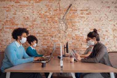 iş arkadaşları dizüstü bilgisayarda ve tablette çalışıp daktilo yazıyorlar.