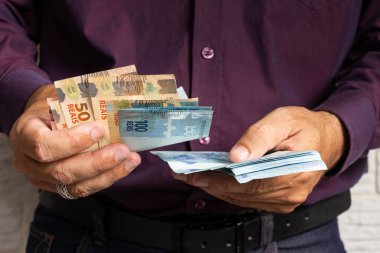 Nakit para sayan bir adamın elleri, Brezilya parası. Finansal, kar, kredi, maliyet, satın alma, zengin konsept