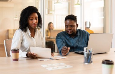 Siyahi iş arkadaşları toplantı odasında işbirliği yapıyor ve tartışıyorlar.