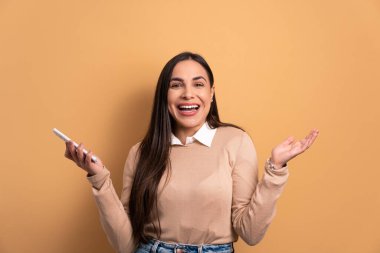 Stüdyoda gülümseyen ve cep telefonu tutan eğlenceli genç bir kadın. uygulama, sosyal medya, bağlantı kavramı.