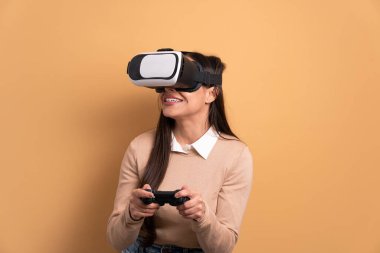 Neşeli Brezilyalı kadın bej renkli stüdyo arka planında VR kulaklıkla video oyunu oynuyor. sanal gerçeklik, oyun, eğlence konsepti.