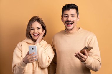 Eğlenceli bir çift cep telefonundan bej renkli video ve fotoğraflar izliyor. uygulama, sosyal medya, bağımlılık, ağ kavramı.