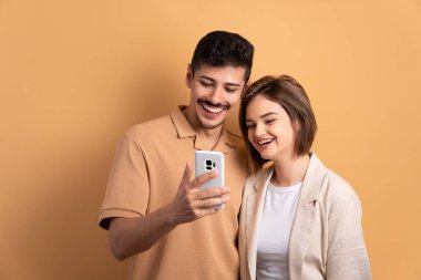 Mutlu çift stüdyo çekimlerinde cep telefonu ekranına bakıyor. uygulama, sosyal medya, bağlantı kavramı.