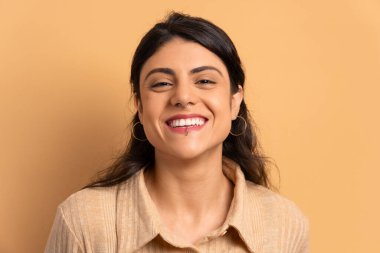 Stüdyoda mutlu bir şekilde gülen neşeli esmer genç kadın. Portre, gerçek insanlar konsepti..
