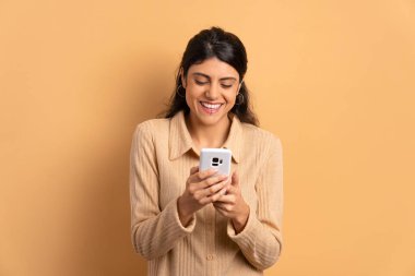 Stüdyoda cep telefonu ekranına bakan neşeli Brezilyalı kadın. uygulama, sosyal medya, bağlantı kavramı.