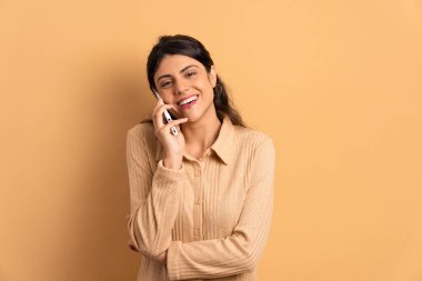 Kafkasyalı mutlu bir kadın cep telefonuyla bej renkli konuşuyor. uygulama, sosyal medya, bağlantı kavramı.