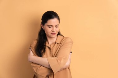 Kendine güvenen Brezilyalı bir kadın kendini kucaklıyor, tüm bej renkleriyle sarılıyor. Kendini sevme, bakım konsepti.