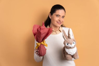 Neşeli Brezilyalı kadın bej arka planda Paskalya yumurtası hediyesini kutluyor. tatil, Paskalya, kutlama konsepti.