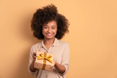 Neşeli siyah kadın bej renkli hediye kutusu veriyor. Noel, mutlu yıllar, kutlama konsepti.