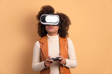 Heyecanlı siyah kadın bej renkli VR kulaklıkla video oyunu oynuyor. sanal gerçeklik, oyun, eğlence konsepti.
