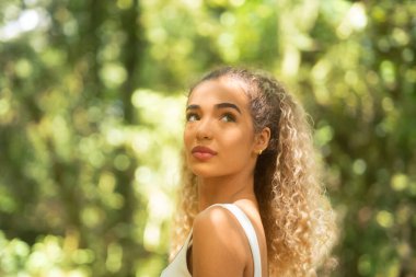 Ormanda doğaya hayran olan genç bir kadın. Atletik giyinen düşünceli kız dışarıda huzurlu bir anın tadını çıkarıyor.