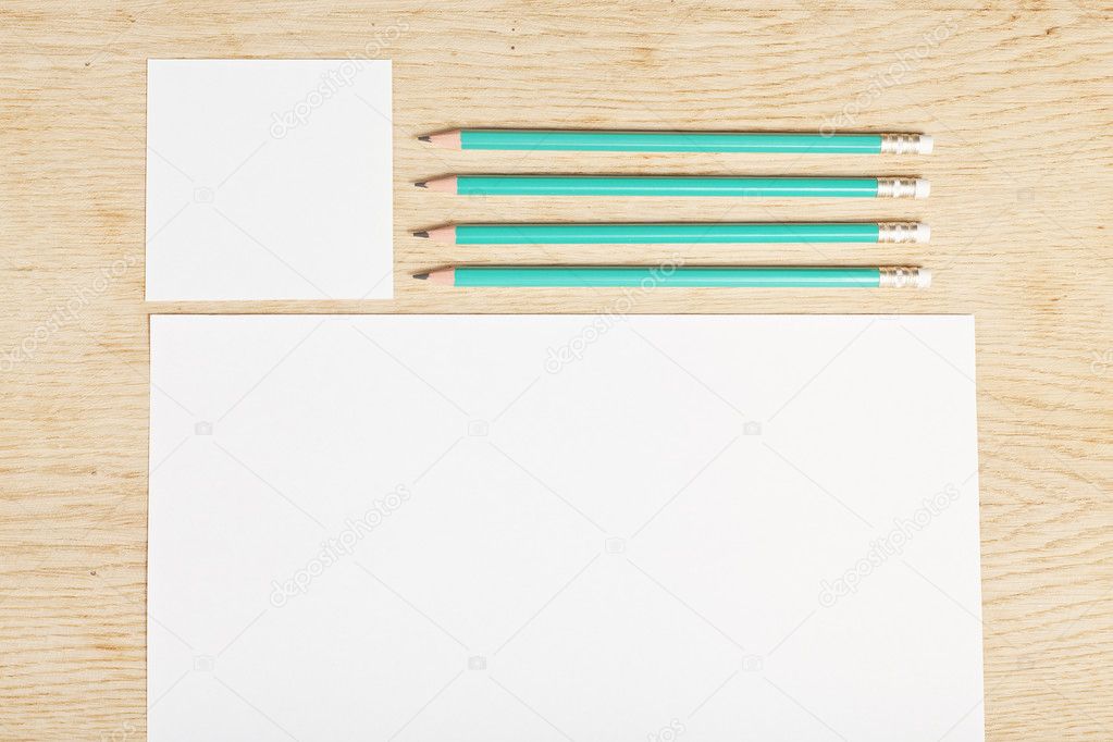 Blanks of empty paper with pencils on a wooden surface.