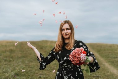 Tarlada kırmızı çiçekleri olan güzel bir kadın.
