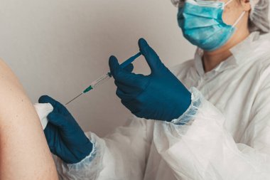 Yüz maskeli kadın doktor elinde kovid 19 aşı tutuyor. 