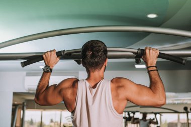 Spor salonunda barfiks çeken genç adam.