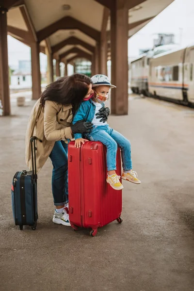 Mother and child with face mask and bags , ready to travel