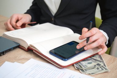 Muhasebeci elinde kitaplarla, cep telefonuyla hesaplama yapıyor.