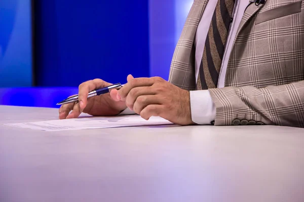 tv host tv reporter tv journalist hands writing down on paper with pen in tv studio suit formal clothing