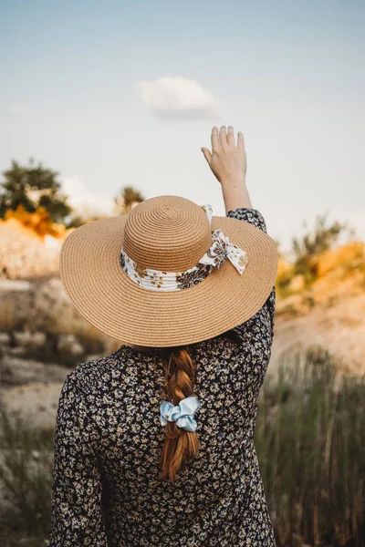 Şapkalı kadın bulutlara dokunuyor.