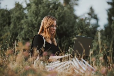 Dizüstü bilgisayarda çalışan mutlu kadın serbest yazar, doğanın uzak bir köşesinde.