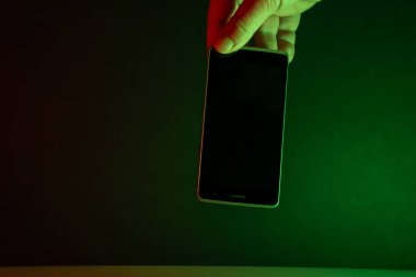 El ele tutuşan cep telefonu, yeşil ışıklar koyu arkaplan