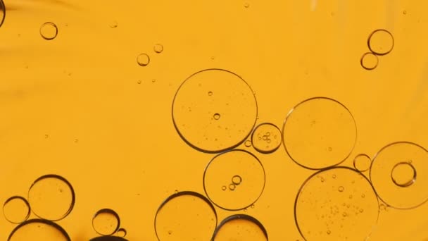 黄色の油滴は水の上に浮かんでいます アブストラクトバブルの背景 オイルドロップのオレンジの背景 — ストック動画