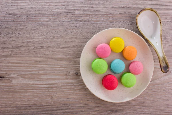 Macarrones dulces y coloridos sobre un fondo de madera — Foto de Stock