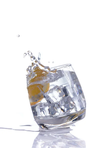 Πορτοκαλί εκτινάξεις σε ποτήρι νερό σε άσπρο φόντο — Φωτογραφία Αρχείου