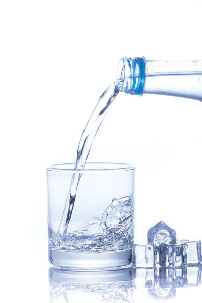 L'acqua viene versata in un bicchiere con cubetti di ghiaccio — Foto Stock
