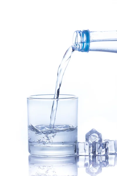 Water is gegoten in een glas met ijsblokjes — Stockfoto