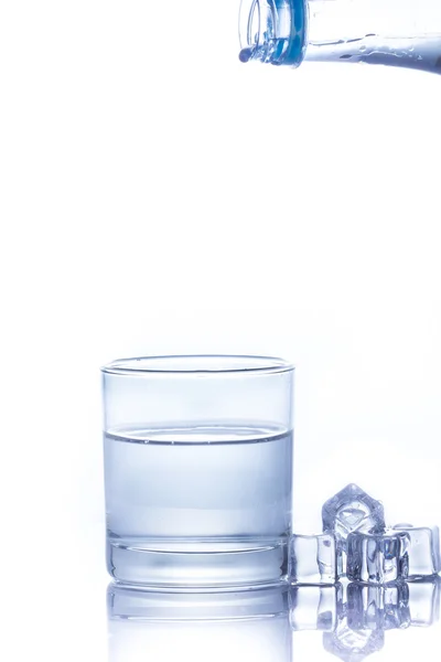 Water is poured into a glass with ice cubes — Stock Photo, Image