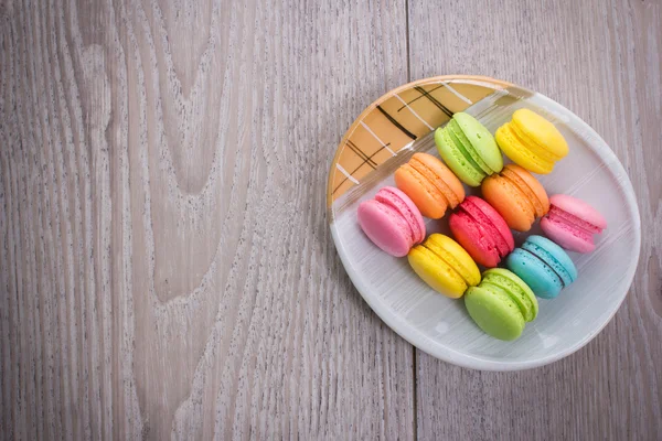 Macarrones dulces y coloridos sobre un fondo de madera — Foto de Stock