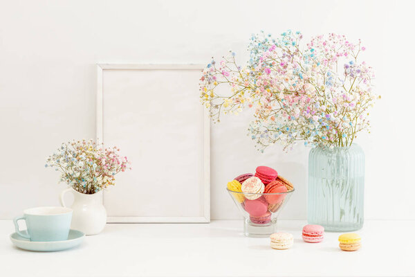 Sweet colorful macarons and flower gypsophila with white frame on table. 