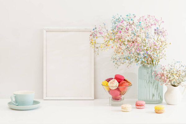 Sweet colorful macarons and flower gypsophila with white frame on table. 