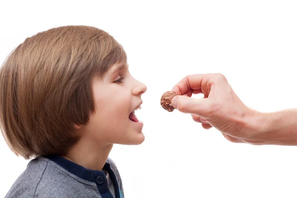Boy bites chocolate ball — Stock Photo, Image