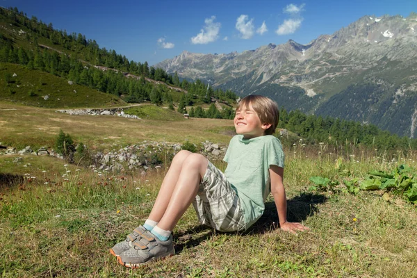 Smiling boy sits on slope — Stock Photo, Image