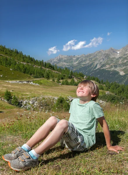 Niño sonriente se sienta en la pendiente — Foto de Stock