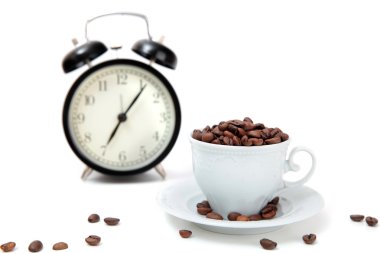 Çalar saat ve beyaz fincan kahve çekirdekleri ile
