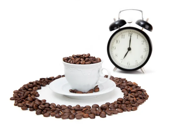 Relógio despertador e xícara branca com grãos de café — Fotografia de Stock