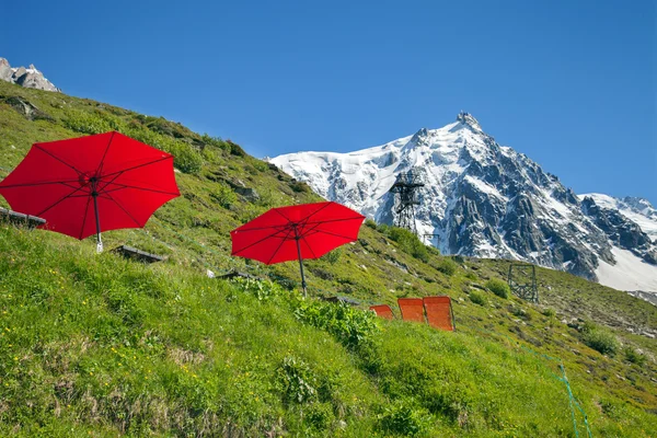 Red umbrellas and lounges in mountain cafe — Stock Photo, Image